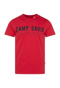 Red cotton t-shirt featuring black printed text "CAMP DAVID REGISTERED TRADEMARK AUTHENTIC STYLE" on the front. Short sleeves, crew neck design.
