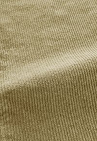 Olijfgroene corduroy stof met een verticale ribbelstructuur, zachte uitstraling en een iets fuzzy afwerking. Ideaal voor bekleding of kleding.