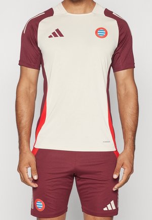 Torse d'homme portant une tenue d'entraînement du FC Bayern Munich bordeaux et beige, avec des manches courtes, des écussons de logo et la marque Adidas.
