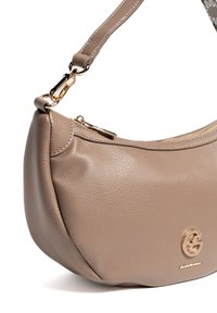 Bolso de cuero marrón claro con forma curva, herrajes dorados y detalles de cremallera. Presenta un logotipo prominente en la parte frontal. Textura suave.