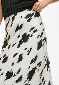 Jupe à imprimé léopard en blanc, avec des taches abstraites noires et brunes. Fabriquée en tissu doux avec un design fluide et une taille élastique.