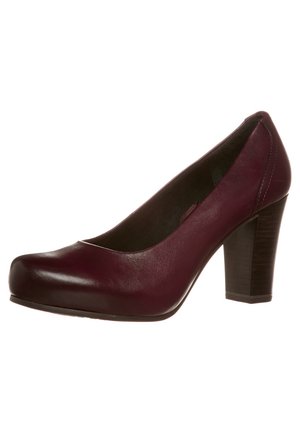 Escarpin en cuir bordeaux avec un bout arrondi, un devant légèrement surélevé et un talon épais. Surface lisse avec des détails de couture minimaux.