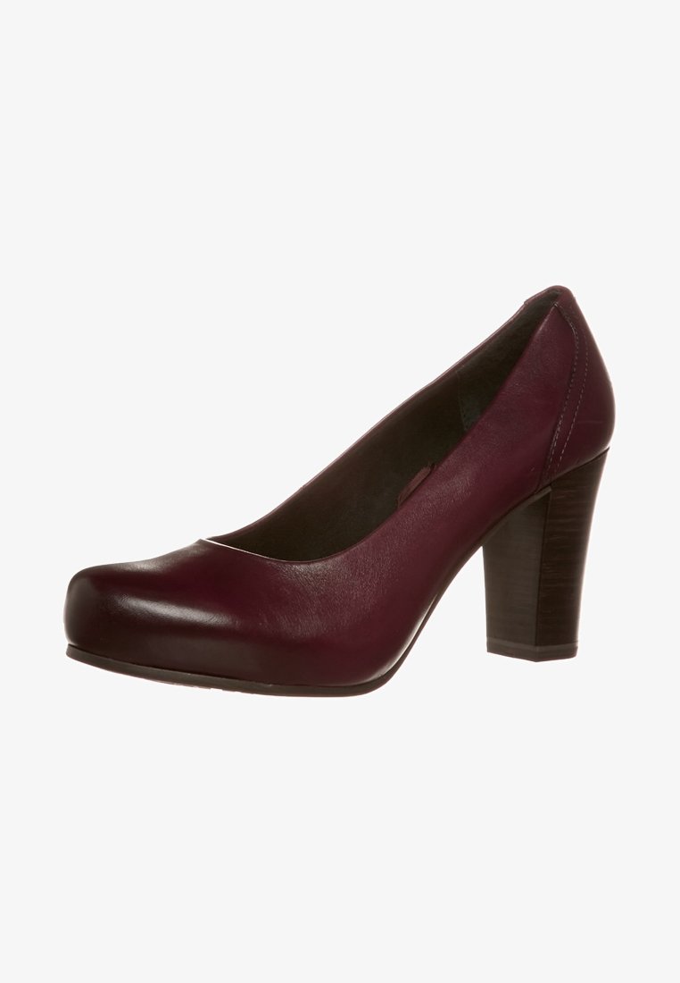 Escarpin en cuir bordeaux avec un bout arrondi, un devant légèrement surélevé et un talon épais. Surface lisse avec des détails de couture minimaux.