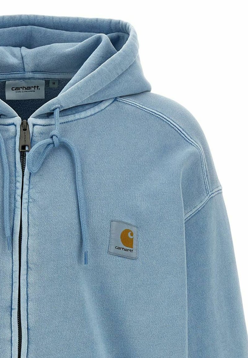 Sweat à capuche zippé Carhartt bleu clair avec cordons et écusson logo sur la poitrine gauche, vu de face et du haut du torse.