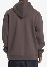 Bruine hoodie met een aantrekbare capuchon, oversized pasvorm, ribgebreide boorden en onderrand, en een zachte textuur, met een schone achterkant.