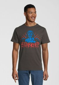 Camiseta de color gris oscuro con un gráfico de un personaje estilizado con elementos azules y rojos, de manga corta, cuello redondo y material de algodón.