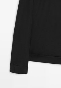 Indumento nero a maniche lunghe con polsini e orlo dritto su uno sfondo bianco.