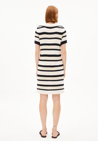 Stickad randig klänning med svarta och krämfärgade horisontella ränder, korta ärmar och rund halsringning, som når mitt på låret.