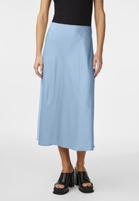 Vaaleansininen satiininen maksihame, jossa on sileä tekstuuri, yksinkertainen muotoilu ja suora siluetti, yhdistettynä mustiin korokepohjaisiin sandaaleihin.