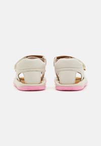 Sandali in pelle grigio chiaro con retro e lati aperti, dotati di una suola rosa, cinturino regolabile e texture morbida. Logo impresso sul tallone.