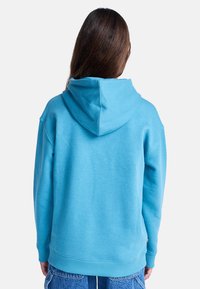 Sweat à capuche bleu clair avec capuche à cordon, poignets et ourlet côtelés, coupe décontractée, en tissu doux. Comprend une étiquette sur le côté.