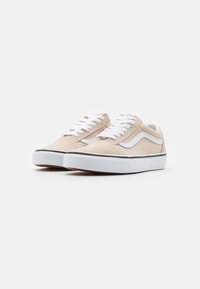 Beige ante sneakers med hvite snørebånd, gummisåler og svart trim. Har et klassisk sidestrek-design. Lav profil, avslappet stil.