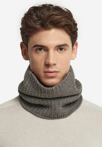 Grå strik cowl-neck tørklæde lavet af tekstureret uld, med et tykt, ribbet mønster. Det er foldet og hænger elegant omkring halsen.