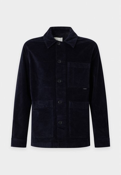 Veste en velours côtelé noire à boutons, avec col, manches longues et trois poches plaquées devant sur un fond uni.