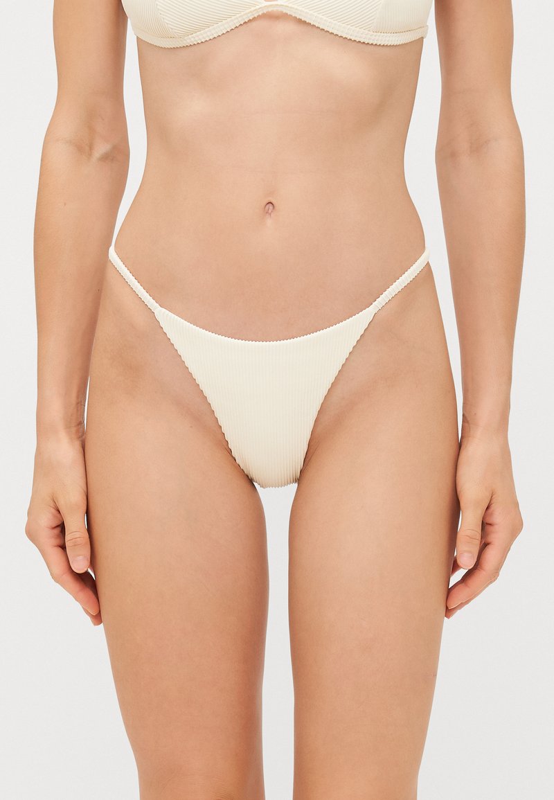Crème-kleurige geribbelde bikini onderkant met dunne zijbandjes, met een minimalistisch ontwerp en een gestructureerde afwerking.