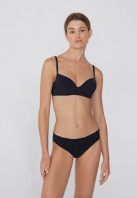 Černý bikinový set obsahující podprsenku s výztuhou a drátky, tenkými ramínky a bezšvovým, nízkým spodním dílem. Materiál je hladký a elastický.