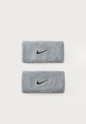 Deux bracelets en éponge gris Nike avec des logos Swoosh noirs sur un fond blanc uni.