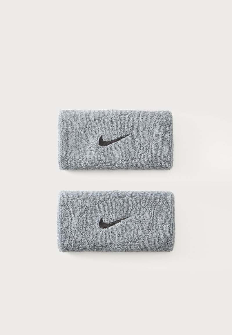 Δύο γκρι μπρασελέ Nike από πετσέτα με μαύρα λογότυπα Swoosh σε απλό λευκό φόντο.
