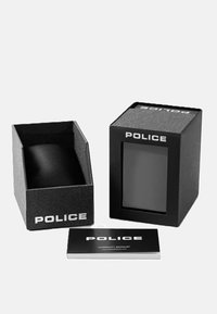 Juodas prezentacinis dėžutė su "POLICE" žymėjimu, atitinkamu minkštu vidiniu laikikliu ir garantiniu knygeliu šviesiame fone.