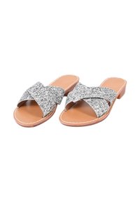 Sandali slip-on in glitter argento con cinture incrociate, soletta beige e tacco basso. Presentano una texture liscia e dettagli cuciti.