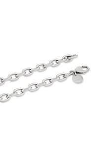 Collana in argento con maglie ovali, chiusura a gancio e un piccolo tag rotondo vicino alla chiusura su sfondo bianco.