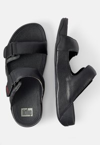 Zwarte leren sandalen met twee verstelbare banden, een gestructureerd oppervlak en een gevoerde zool, met een klein logo op de binnenzijde.