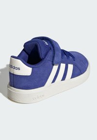 Modré semišové tenisky Adidas s bílou podrážkou, třemi bílými pruhy na straně a uzavíráním na suchý zip na světlém pozadí.