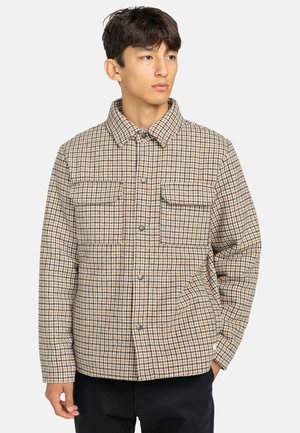 Veste en flanelle à carreaux beige et bleu, avec une fermeture à boutons, deux poches poitrine et un col, fabriquée en tissu texturé.