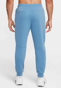 Blue sweatpants with a drawstring waist, featuring a smooth texture and tapered legs. The design includes contrasting knee panel accents.