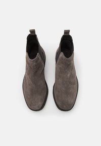 Szare zamszowe botki za kostkę o gładkiej fakturze, elastycznymi bocznymi panelami i pętelką z tyłu. Płaska czarna gumowa podeszwa.