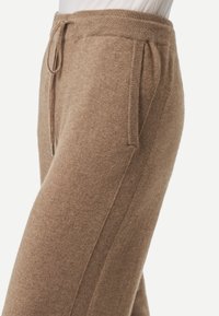 Bruna stickade joggingbyxor med dragsko i midjan, sidfickor och kontrasterande sidopaneler. Mjuk textur och avslappnad passform.