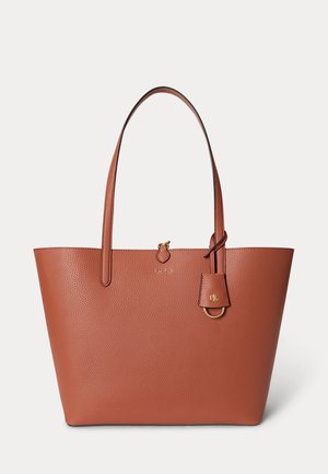 Sac cabas en cuir marron texturé avec deux anses, une petite étiquette suspendue et des accents de logo subtils en ton or.