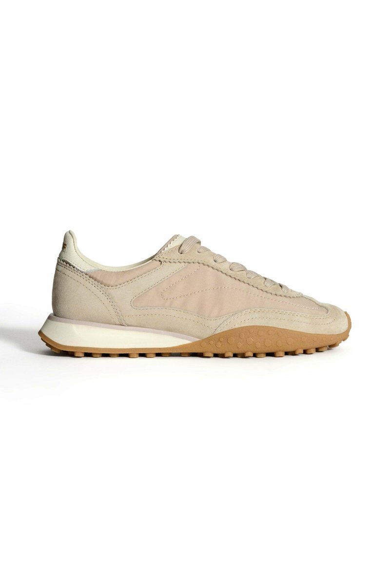 Baskets en daim beige avec une surface texturée, un design à lacets et une semelle en caoutchouc léger dotée de petites grips circulaires.