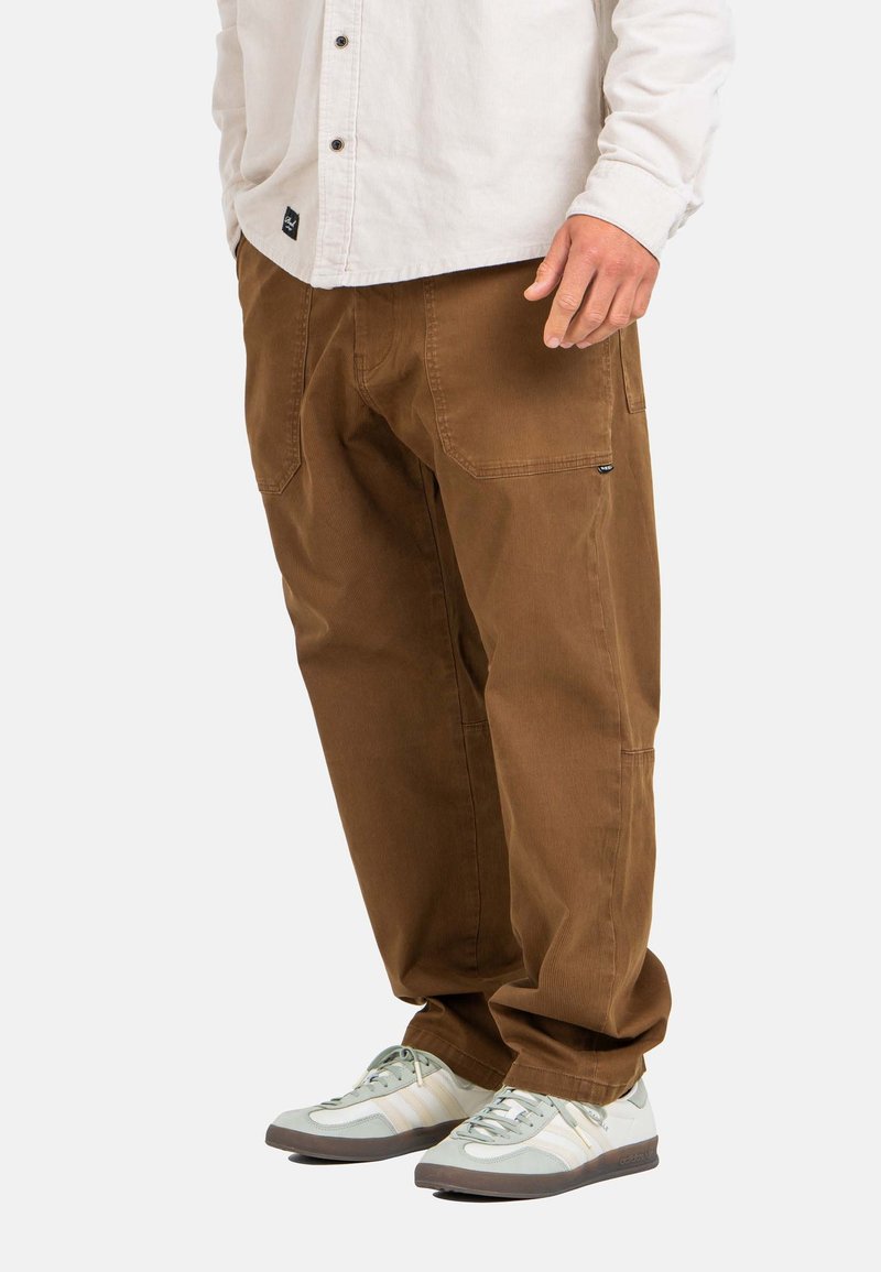 Brown cargo pants made of sturdy fabric, featuring side pockets and a loose fit, paired with light gray and white sneakers.