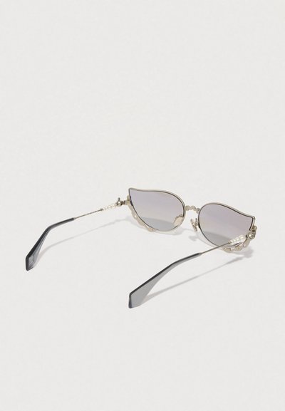 Óculos de sol estilo gato com lentes cinza graduadas, armação metálica, detalhes em pérola e hastes pretas. Design ondulado notável nas bordas da armação.