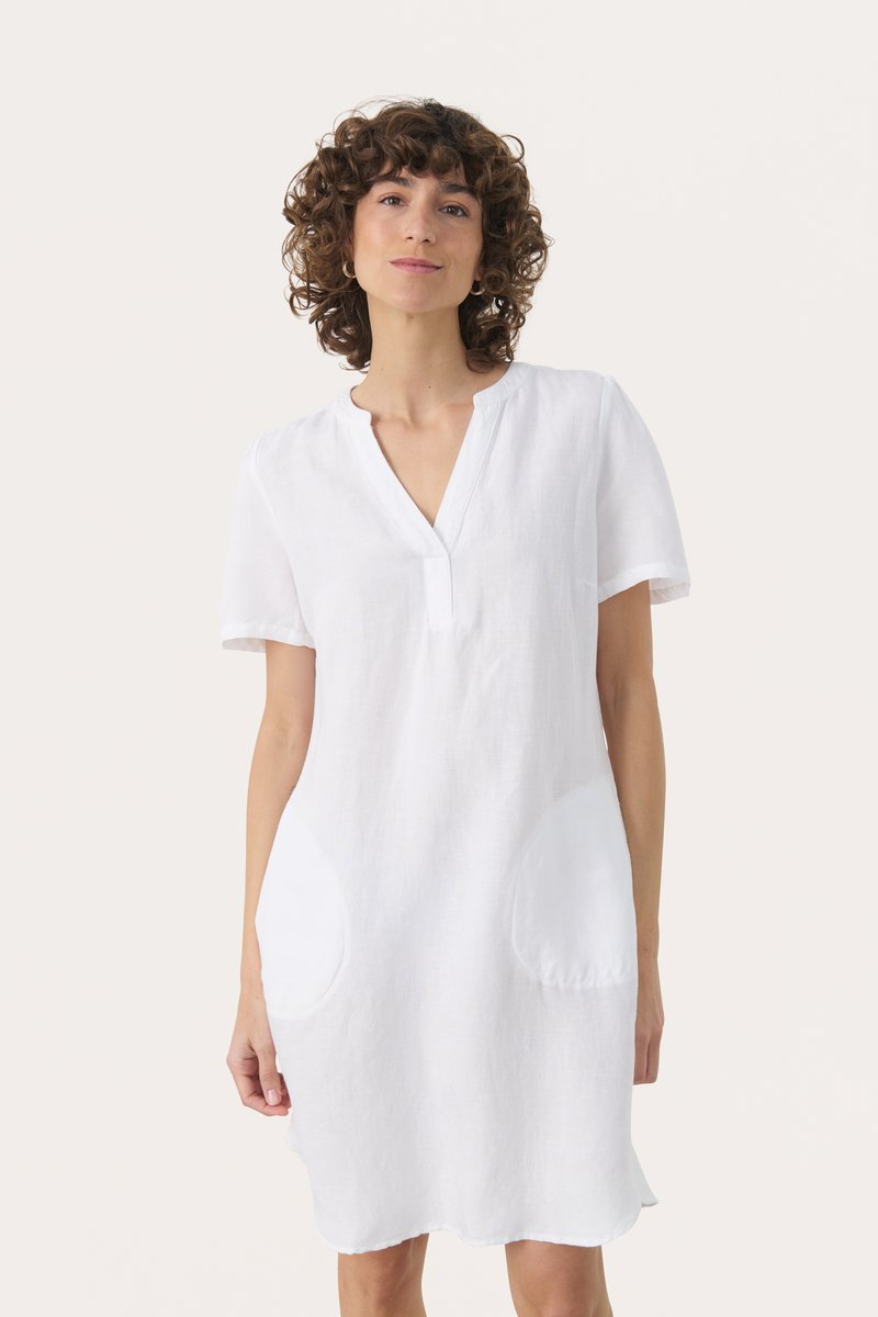 Weißes Leinenkleid mit kurzen Ärmeln, V-Ausschnitt und zwei großen ovalen Taschen. Der Stoff hat ein leicht strukturiertes Aussehen.