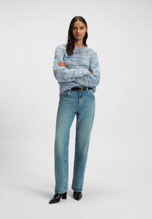 Light blue knitted sweater with a textured pattern, paired with light wash straight-leg jeans and black pointed-toe heeled boots.