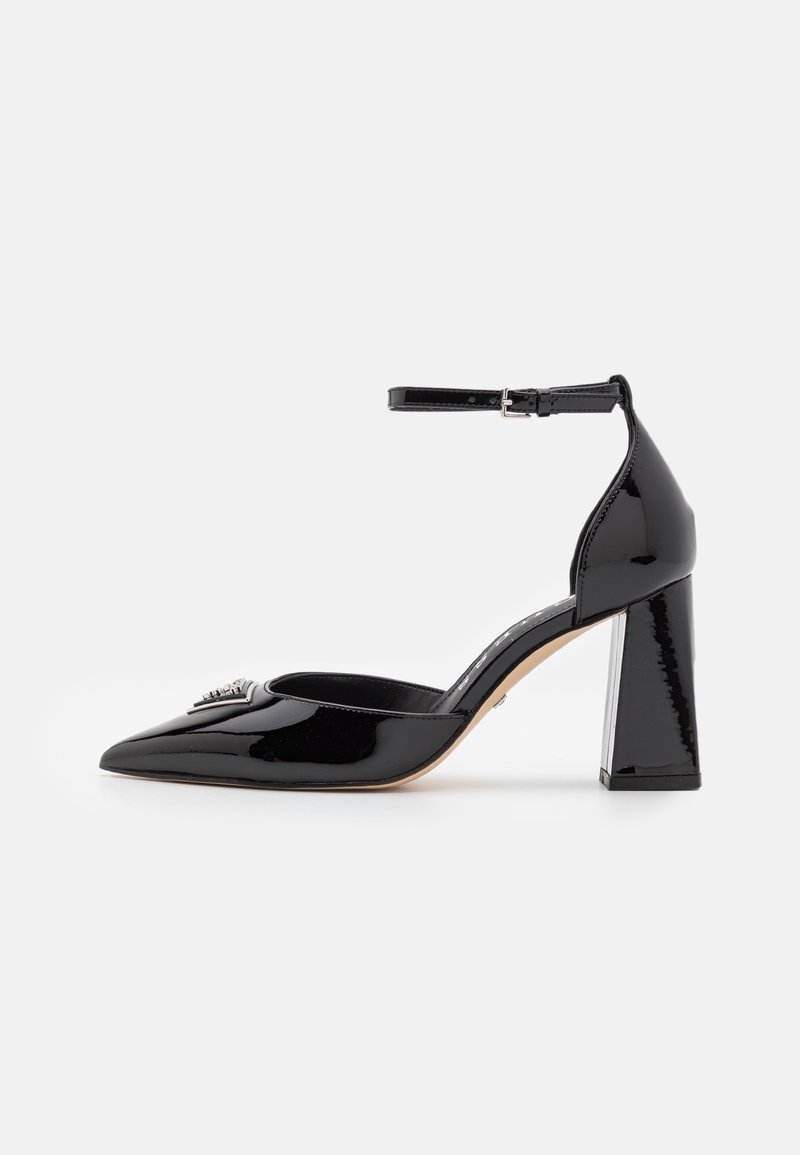 Chaussure à talon haut en cuir verni noir avec bout pointu, talon bloc, bride à la cheville et détail métallique décoratif à l'avant.