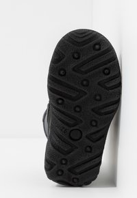 Suola di stivale in gomma nera con una superficie texture caratterizzata da modelli di battistrada, impugnature circolari e linee rialzate per la trazione.
