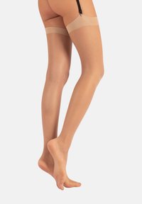 Calze beige a coscia con una texture liscia, dotate di un banda in silicone nella parte superiore per una migliore aderenza. Il materiale trasparente si estende fino a metà coscia.