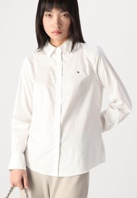 Witte, langärmels button-up shirt van katoen. Heeft een klassieke kraag en een klein logo op de borst. Glad textuur, getailleerd ontwerp.