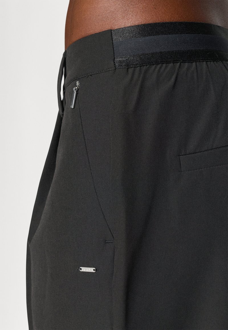 Czarne spodenki wykonane z lekkiego materiału, z elastycznym pasem w ciemny pasek, boczną kieszenią i metalowym zamkiem błyskawicznym.