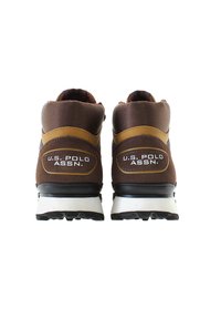 Brązowe buty sportowe wykonane z zamszu i siateczki. Posiadają teksturowaną piętę, żółty akcent w pasie oraz białą gumową podeszwę z żłobieniami zapewniającymi przyczepność.