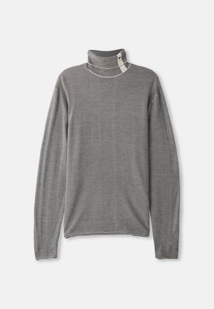 Pull col roulé gris rayé à manches longues. Le tissu a une texture douce. Il se caractérise par un col haut et des accents de couture visibles.