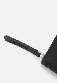 Zwart textuurportemonnee met een ritsen trekker met het reliëf 'Desigual' logo en een zilveren metalen accent. Compact ontwerp met strakke afwerkingen.