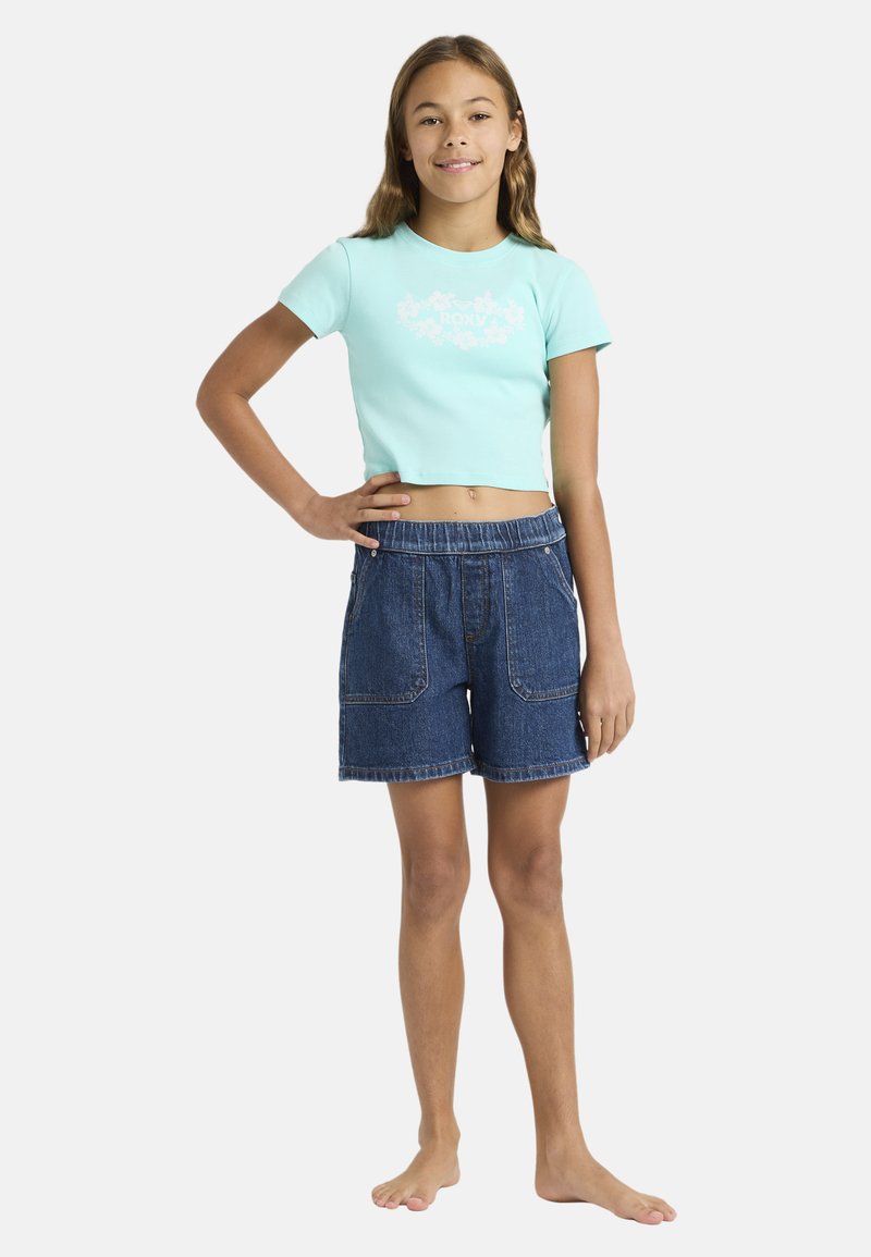 Svetlomodrý crop top s bielou grafikou, skombinovaný s tmavomodrými džínsovými šortkami s prednými vreckami a elastickým pásom.