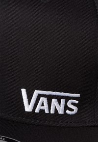 Black cap with embroidered white "VANS" logo. Features structured crown, flat brim, and textured fabric. Classic snapback design.
