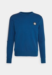 Felpa blu con scollatura rotonda, polsini a costine e una toppa con logo. Presenta strisce bianche lungo le spalle. Realizzata in morbido cotone.