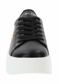 Baskets en cuir synthétique noir avec une semelle plateforme blanche, dotées de lacets noirs et d'un détail logo doré sur le côté.