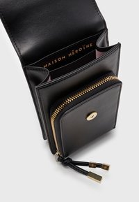 Czarny skórzany portfel z złotym zapięciem na zamek, przegrodą na karty i logo wewnątrz. Charakteryzuje się gładką teksturą i złotymi akcentami.